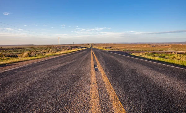 Larga carretera en el desierto americano, cielo azul —  Fotos de Stock