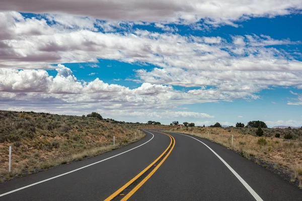 Lunga strada tortuosa nella campagna americana, cielo blu con nuvole — Foto Stock