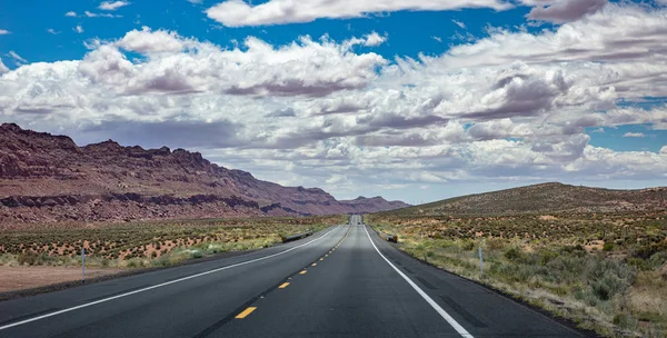 Long highway with ups and downs, cloudy blue sky. USA — Stock Photo, Image