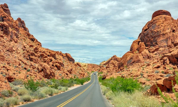Iniş ve iniş, bulutlu mavi gökyüzü ile uzun dolambaçlı karayolu. Valley of Fire Nevada, Amerika Birleşik Devletleri