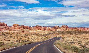 Iniş ve iniş, bulutlu mavi gökyüzü ile uzun dolambaçlı karayolu. Valley of Fire Nevada, Amerika Birleşik Devletleri
