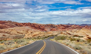 Iniş ve iniş, bulutlu mavi gökyüzü ile uzun dolambaçlı karayolu. Valley of Fire Nevada, Amerika Birleşik Devletleri