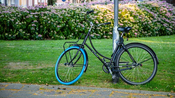 Bicicleta apoiada em um poste de metal na cidade de Rotterdam, Países Baixos — Fotografia de Stock
