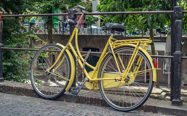 Κίτρινο χρώμα ποδηλάτου κλειδωμένο σε ένα κιγκλίδωμα ποταμού κανάλι στην Ουτρέχτη πόλη, Ολλανδία — Φωτογραφία Αρχείου
