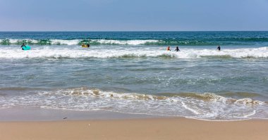Sörfçü sörf, güneşli bir bahar gününde okyanus deniz dalgaları gidiyor