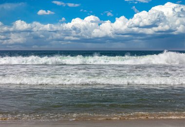 Kumlu plaj boş. Mavi bulutlu gökyüzü, dalgalar ile mavi deniz