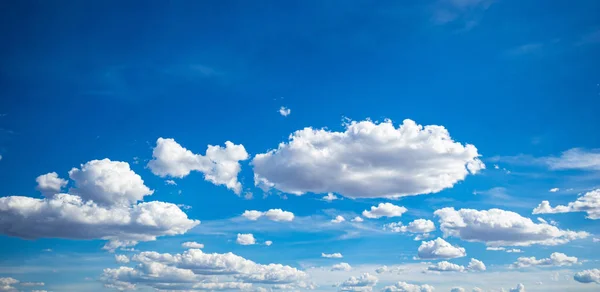 Blauwe hemel achtergrond met wolken, zonnige lente dag — Stockfoto