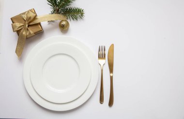 Masa ayarı, xmas, yeni yıl. Beyaz tabak seti üzerine altın çatal bıçak takımı, beyaz arka plan