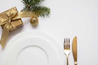 Masa ayarı, xmas, yeni yıl. Beyaz tabak seti üzerine altın çatal bıçak takımı, beyaz arka plan