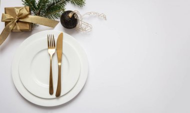 Masa ayarı, xmas, yeni yıl. Beyaz tabak seti üzerine altın çatal bıçak takımı, beyaz arka plan