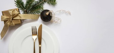 Masa ayarı, xmas, yeni yıl. Beyaz tabak seti üzerine altın çatal bıçak takımı, beyaz arka plan