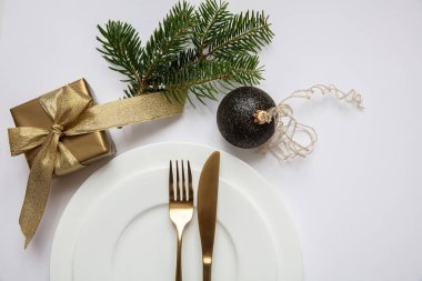 Masa ayarı, xmas, yeni yıl. Beyaz tabak seti üzerine altın çatal bıçak takımı, beyaz arka plan