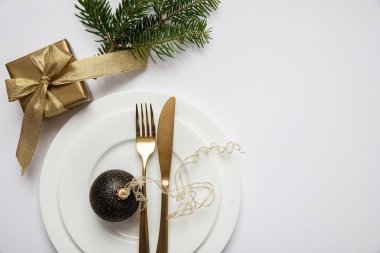 Masa ayarı, xmas, yeni yıl. Beyaz tabak seti üzerine altın çatal bıçak takımı, beyaz arka plan