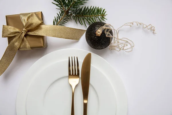 Masa ayarı, xmas, yeni yıl. Beyaz tabak seti üzerine altın çatal bıçak takımı, beyaz arka plan