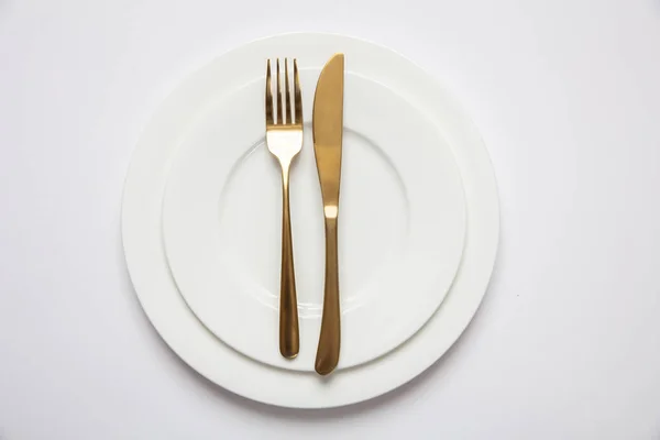 Montagem da mesa, formal. Talheres de ouro em conjunto branco de pratos, fundo branco — Fotografia de Stock