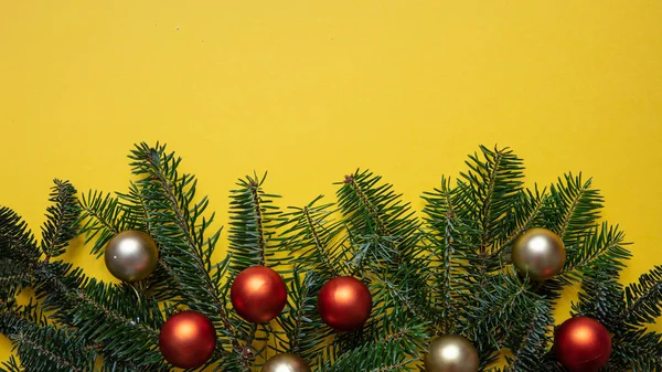 Brindille de sapin boules fraîches et de Noël sur fond de couleur jaune — Photo