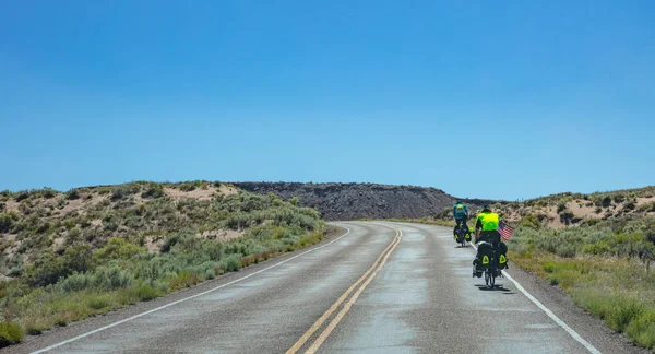 Vue arrière des cyclistes à vélo près de la forêt pétrifiée, ensoleillé le jour du printemps, Arizona États-Unis . — Photo