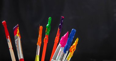 Siyah arkaplan üzerinde renkli boya fırçaları, yakın plan görünümü, boşluk kopyala