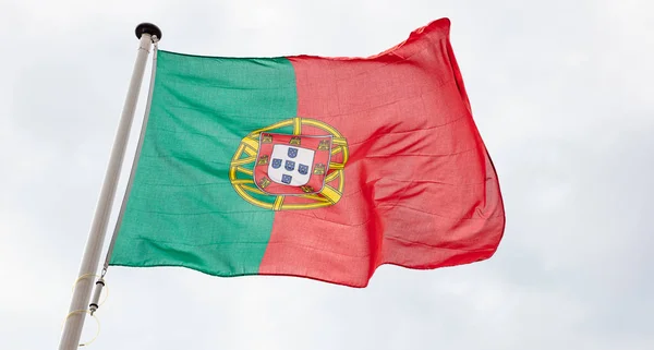 Bandeira portuguesa acenando contra fundo céu nublado — Fotografia de Stock