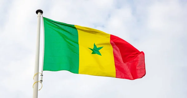 Bandeira senegalesa acenando contra fundo céu nublado — Fotografia de Stock