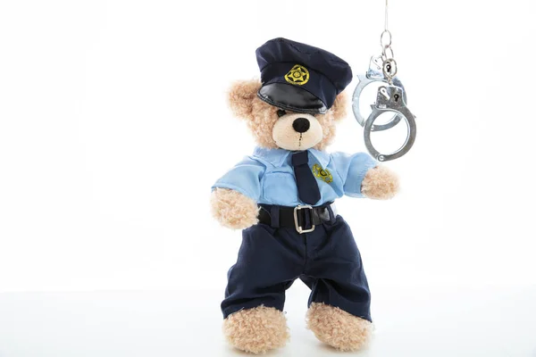 Schattig teddy in politie uniform en handboeien geïsoleerd tegen witte achtergrond — Stockfoto