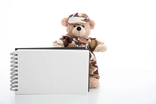 Schattige teddybeer in soldaat uniform en een blanco pad geïsoleerd tegen witte achtergrond — Stockfoto
