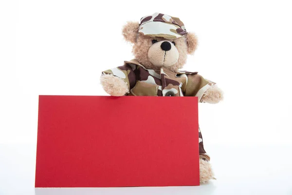 Schattige teddybeer in soldaat uniform en een blanco rode kleur kaart geïsoleerd tegen witte achtergrond — Stockfoto