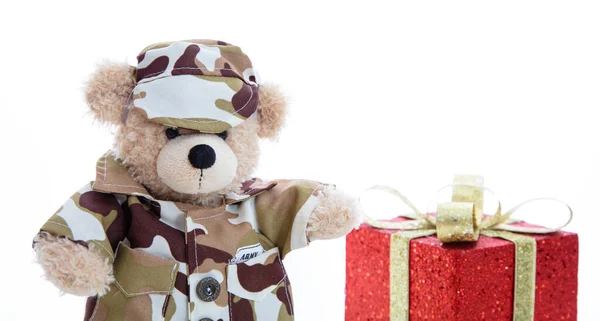 Leuke teddybeer in soldatenuniform en een rood cadeau geïsoleerd tegen witte achtergrond — Stockfoto