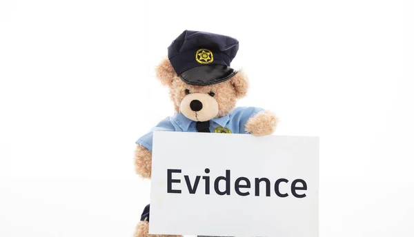 Schattig teddy in politie uniform en bewijs tekst op een papier geïsoleerd tegen witte achtergrond — Stockfoto