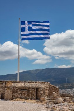Atina Akropolü, Yunanistan. Direkte dalgalanan Yunan bayrağı, mavi gökyüzü arkaplanı, ilkbahar güneşli günü, dikey fotoğraf.