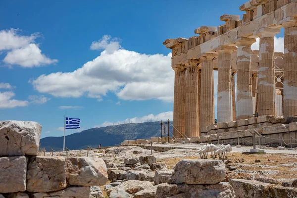 Athens Acropolis, Greece. Parthenon temple and greek flag waving against blue sky background, spring sunny day.