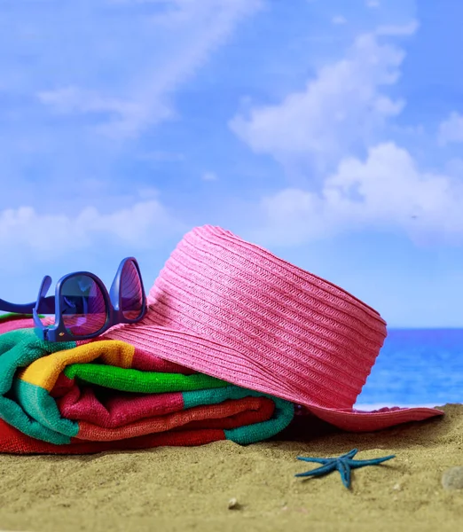 Summer vacation by the sea concept. Beach accessories on a the seaside. Blue sea and sky background. Vertical photo, closeup view.