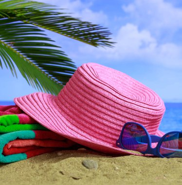 Deniz konseptiyle yaz tatili. Deniz kenarındaki plaj aksesuarları. Mavi deniz ve gökyüzü arka planı. Dikey fotoğraf, yakın görüntü.