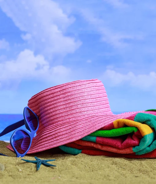 Summer holidays by the sea concept. Beach accessories on a the seaside. Blue sea and sky background. Vertical photo, closeup view.