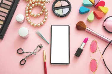 Kadın aksesuarları ve beyaz ekranlı akıllı telefon pembe renkli arka plan, düz yatış, üst manzara. Moda blogcusu çalışma alanı, kopyalama alanı