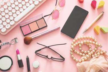 Bilgisayar dizüstü bilgisayarı ve kadın aksesuarlarıyla moda blogcusu çalışma alanı. Pembe arkaplan, düz yatak, üst görünüm karşı kadın ürünleri.