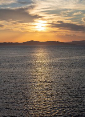 Deniz suyunun üzerinde gün batımı turuncu bulutlar. Ege Denizi Yunanistan 'da dramatik büyülü gündoğumu deniz manzarası. Karanlık ada kara ufku, alacakaranlık, şafak arkaplanı.