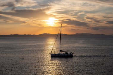 Yunanistan, Ege Denizi 'nde gün batımında denize açılacağız. Sakin denizde yelkenli ve turuncu gökyüzü arka planında,