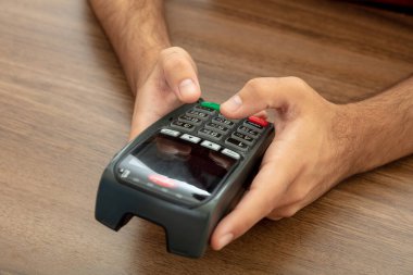 Ödeme makinesi ve daktilo makinesi tutan adam, yakın çekim. Kredi kartı okuyucu, POS terminal ödeme kavramı.