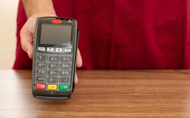 Kasiyer, ödeme için POS terminalini kredi kartıyla sunuyor. Bankacılık, alışveriş ve NFC teknoloji konsepti ile irtibatsız ödeme.