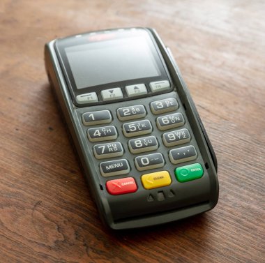 POS terminali ahşap arka planda izole edildi, yakın çekim görüntüsü. Kredi kartıyla ulaşılamayan ödemeler için terminal yazar kasası. Banka ekipmanları, NFC.