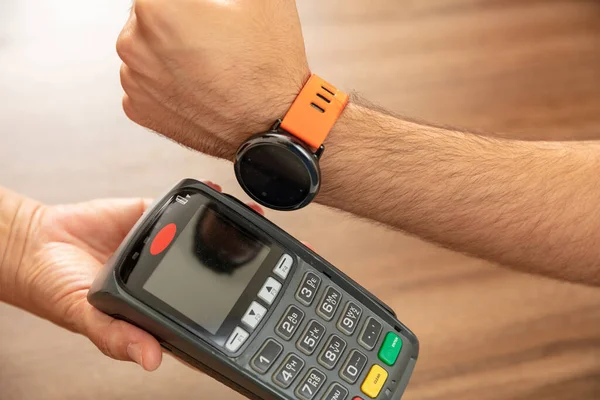 Mobil ödeme, akıllı saat NFC, saha iletişimi kablosuz teknolojisi. POS makinesi ve akıllı saat ile kasiyer ve müşteri elleri, yakın görünüm