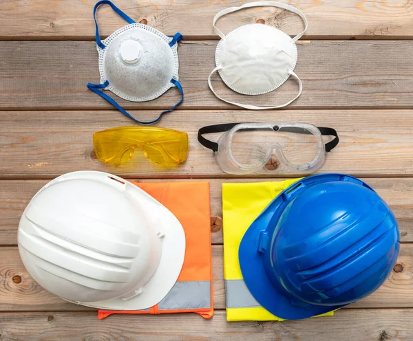 Work safety protection equipment. Industrial protective gear for two on wooden background. Construction site health and safety concept