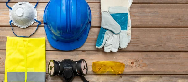 Work safety protection equipment. Industrial protective gear on wooden background. Construction site health and safety concept