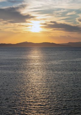 Deniz suyunun üzerinde gün batımı turuncu bulutlar. Ege Denizi Yunanistan 'da dramatik büyülü gündoğumu deniz manzarası. Karanlık ada kara ufku, alacakaranlık, şafak arkaplanı.