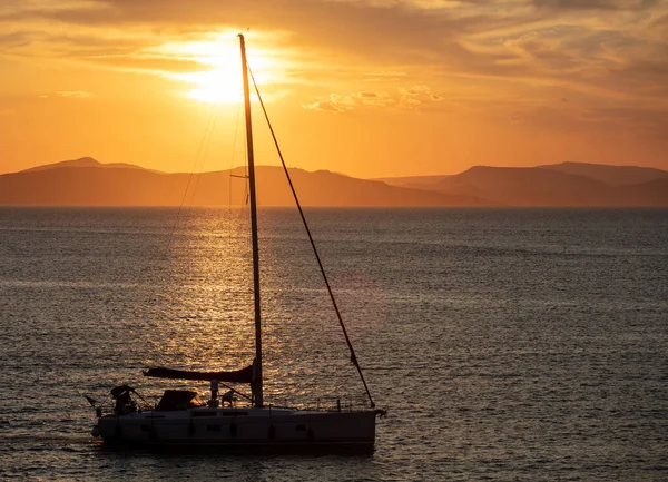 Sailing at sunset in the Aegean sea, Greece. Sailboat on calm sea and orange sky background,