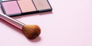 Allık tozu paleti, pastel renkler ve pembe arka plana sürtünme, yakın görüş. Makyaj malzemeleri, güzellik salonu, kozmetik konsepti.