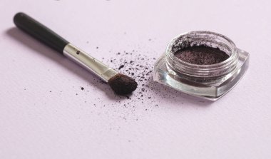 Göz farı mor ve pembe arkaplan üzerinde fırça, yakın görüş. Makyaj malzemeleri, güzellik salonu, kozmetik konsepti.
