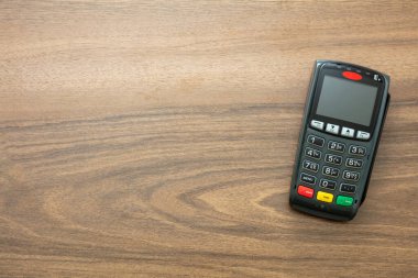 POS terminali ahşap arka planda, üst görüntüde izole edildi. Kredi kartıyla ulaşılamayan ödemeler için terminal yazar kasası. Banka ekipmanları, NFC.