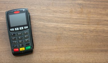 POS terminali ahşap arka planda, üst görüntüde izole edildi. Kredi kartıyla ulaşılamayan ödemeler için terminal yazar kasası. Banka ekipmanları, NFC.